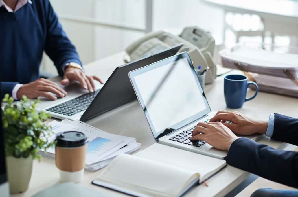 Close-up of hands typing on a laptop in a business meeting