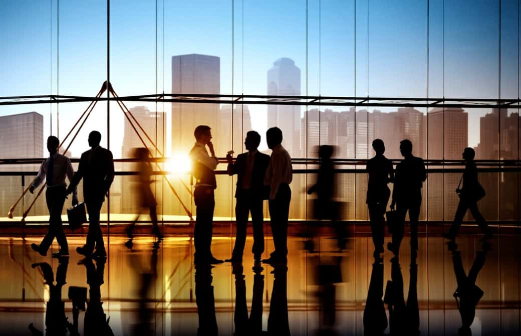 Silhouettes of business people conversing in a sunlit office lobby