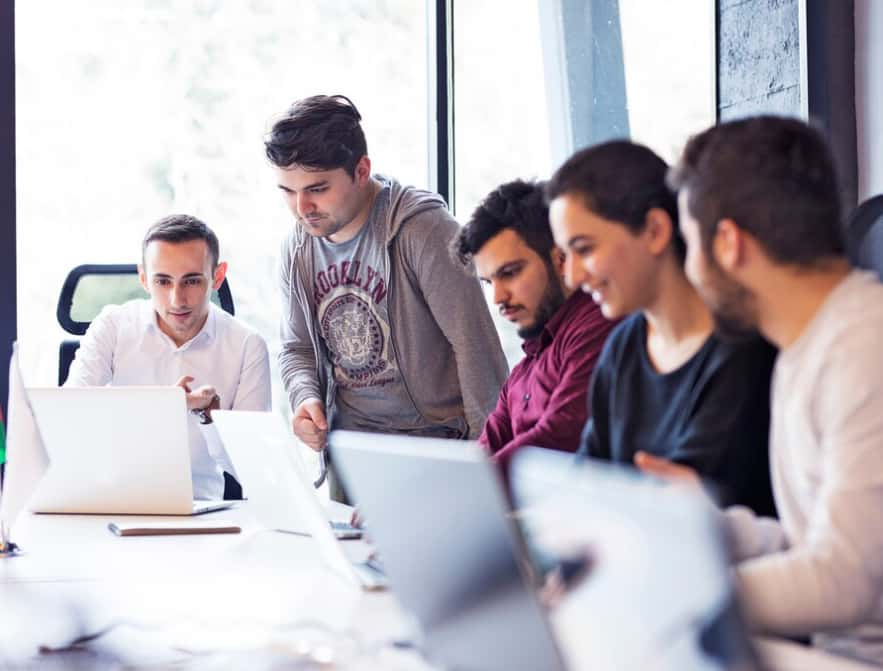 A group of professionals collaboratively working around laptops