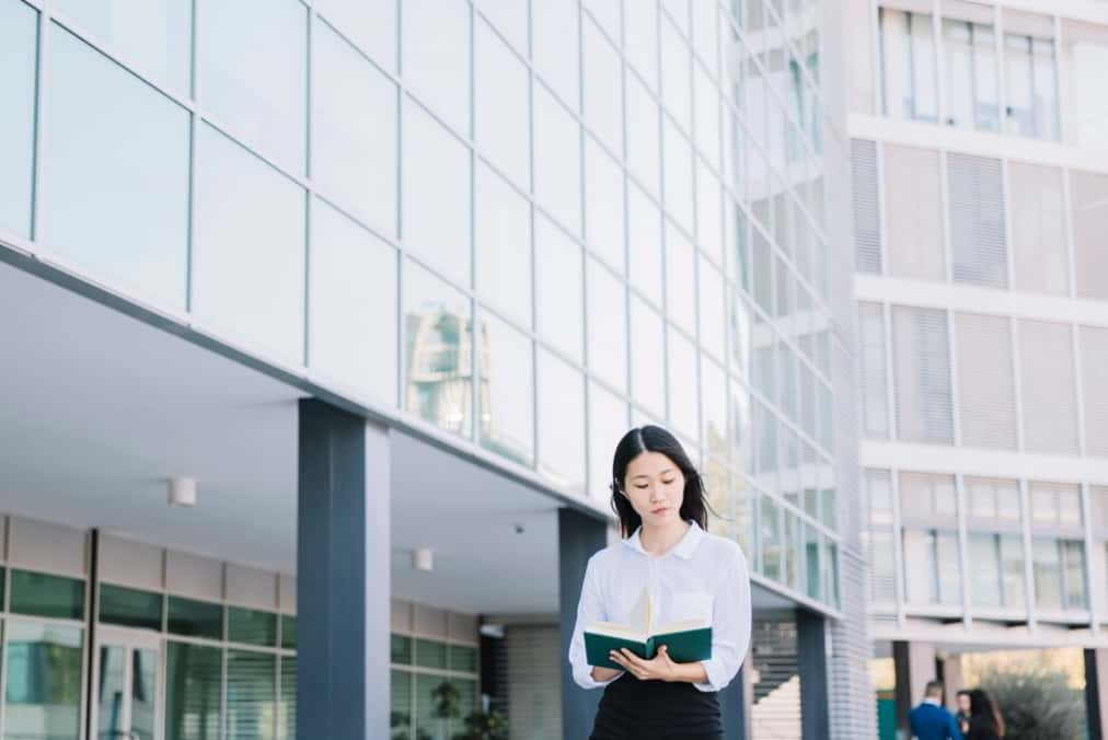 A thoughtful woman walking past a building with a glass facade